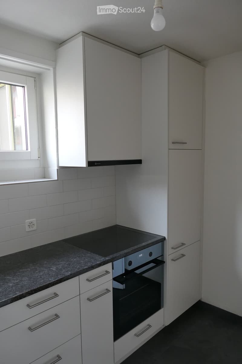 Modern kitchen with white cabinets, granite countertop, induction cooktop, and built-in oven.
