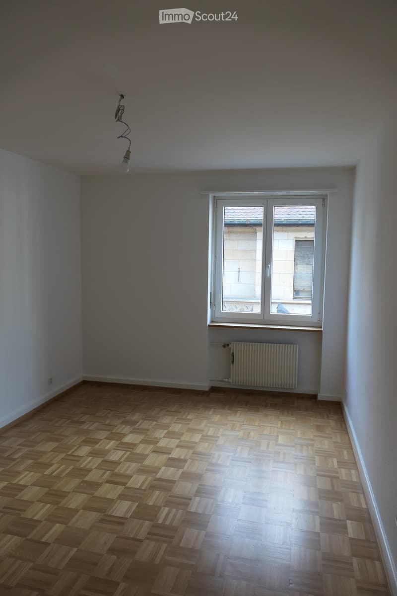 empty room, hardwood floor, radiator, windows, light fixture