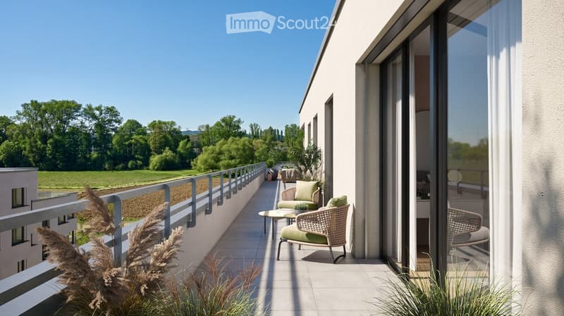 Balcony with modern furniture, including a wicker chair and small table, overlooking a green landscape.