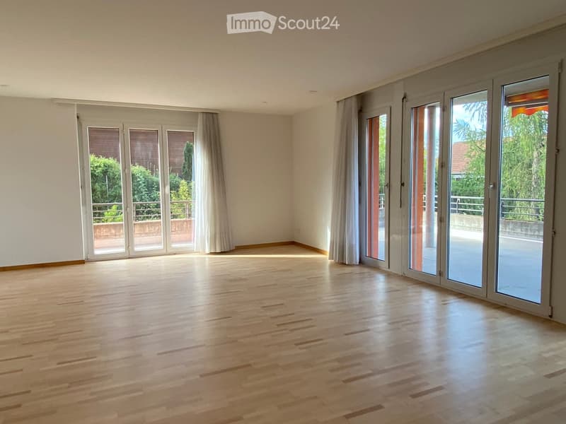 Empty room with wooden flooring, large sliding glass doors, and white walls.