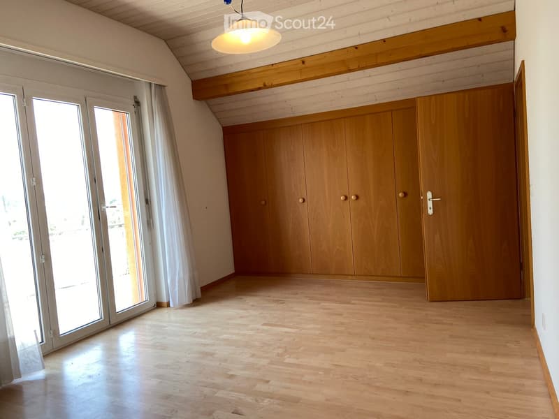 Empty room with wooden flooring, large sliding glass doors, built-in wooden cabinetry, and a pendant light fixture.