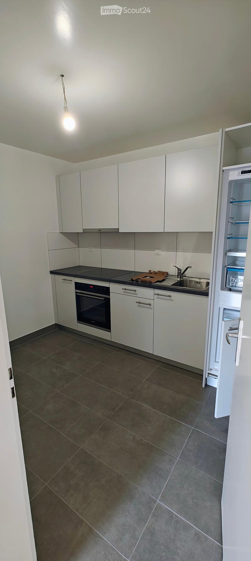 Modern kitchen with white cabinets, dark countertops, and stainless steel appliances including a refrigerator, oven, and sink.