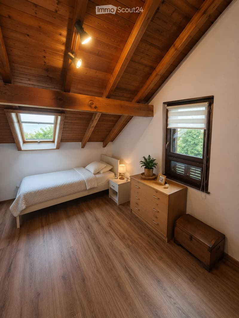 Cozy attic bedroom with wooden slanted ceilings, exposed beams, and wooden flooring. Features a single bed, nightstand with lamp, dresser with drawers, small plant, and a wooden chest.