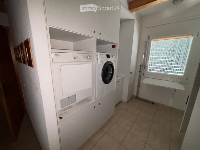 Small bathroom with tiled floor, white walls, and a stacked washing machine and dryer unit.