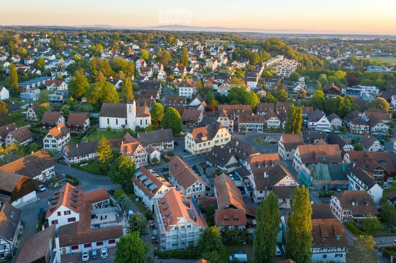 Aerial view of a residential neighborhood with numerous houses, trees, and a church in the center.