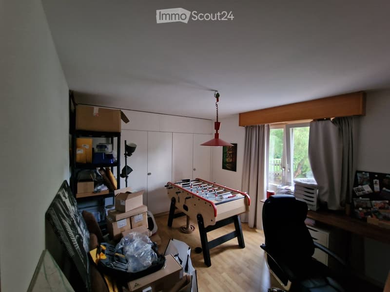 Room with wooden flooring, foosball table, chair, shelf, cabinet, and lamp.
