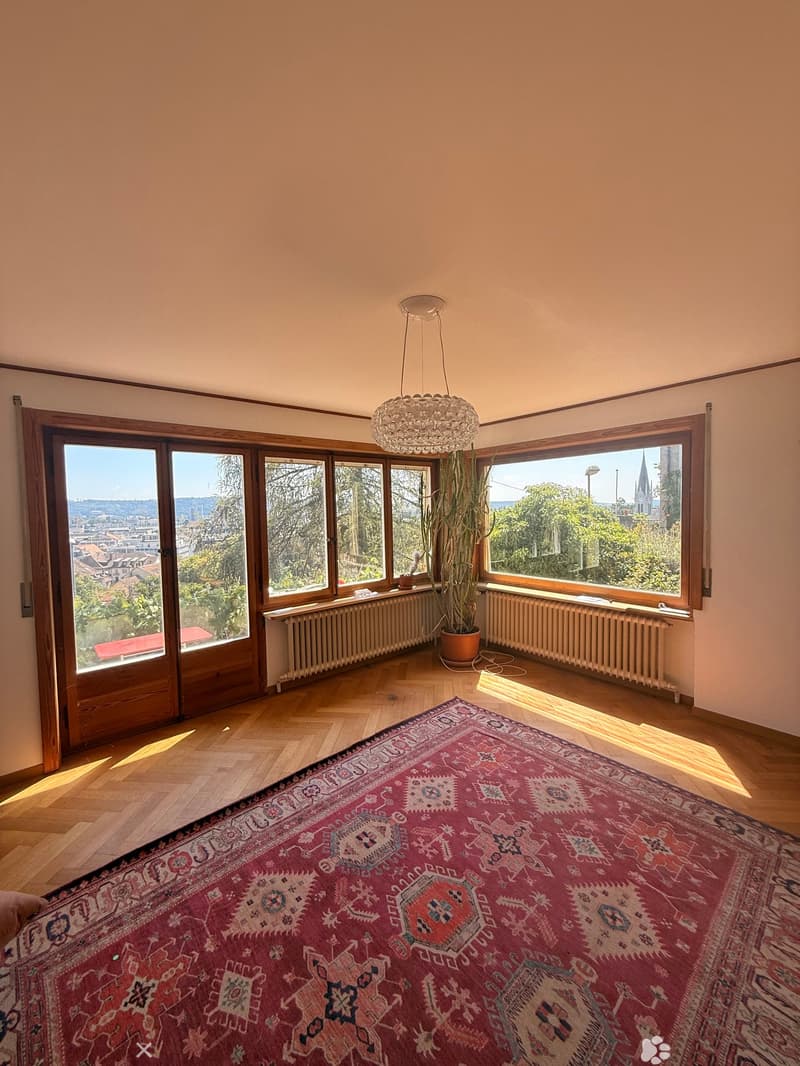 Empty room with wooden flooring, large windows, and a chandelier. No furniture or equipment present.
