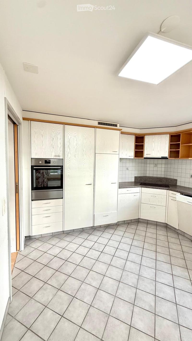 Modern kitchen with white cabinets, stainless steel oven, tiled floor, and countertop.
