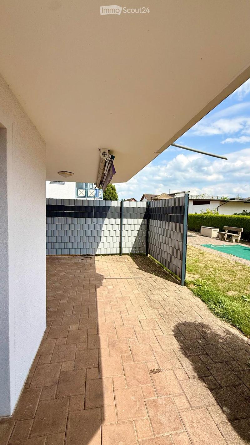 Outdoor patio area with tiled flooring, covered roof, and a gated entrance leading to a grassy area and swimming pool.