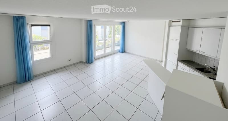 Empty room with white tiled flooring, white cabinets, and a sliding glass door leading to a balcony.