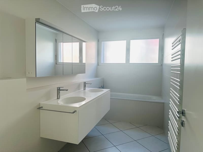 Bathroom. Modern bathroom with a white double sink, sleek faucets, a large mirror, and a radiator on the wall.