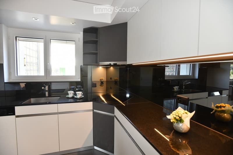 Modern kitchen with white and black cabinets, dark countertops, stainless steel sink, and decorative vases on the counter.