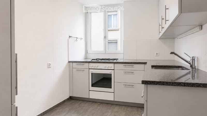 Modern kitchen with white cabinets, stainless steel appliances, granite countertops, and a window above the sink.