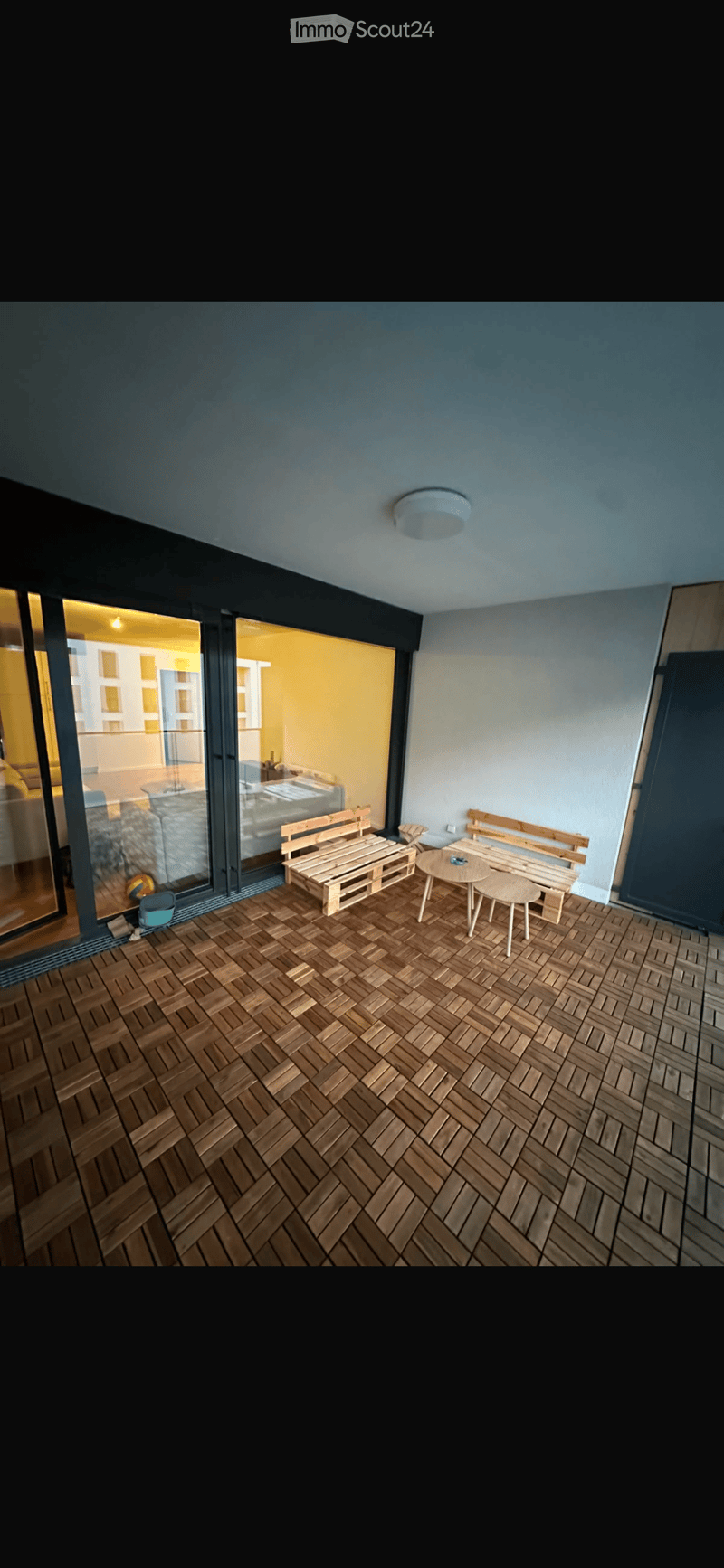 Balcony with wooden decking, two benches, and a small round table.