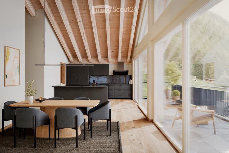 Modern kitchen with wooden dining table, grey chairs, dark kitchen cabinets, pendant light, and large windows offering a scenic view.