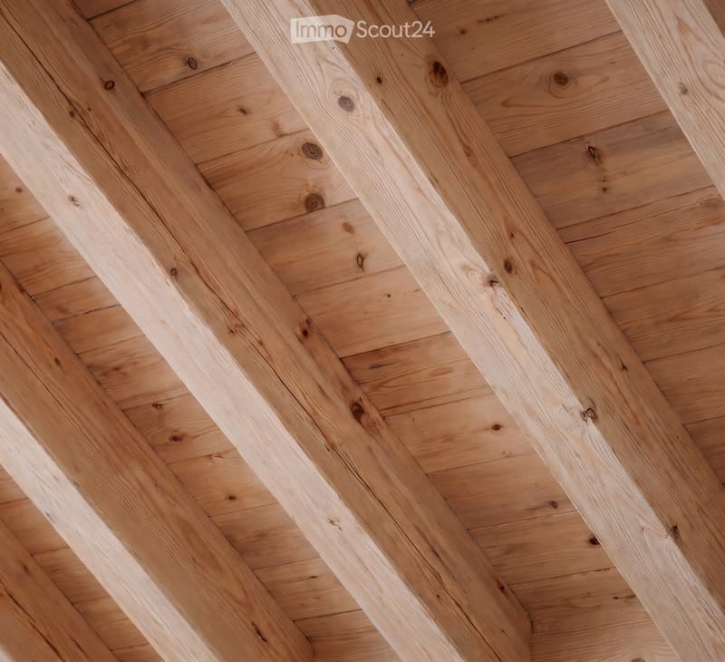Close-up view of a wooden ceiling with exposed beams and planks, showcasing natural wood grain and knots.
