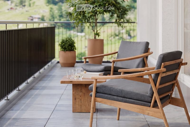 Balcony with two wooden chairs, a small wooden table, two glasses, and two potted plants.