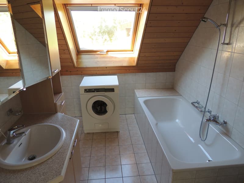 Bathroom with a bathtub, sink, washing machine, and wooden ceiling with skylights.