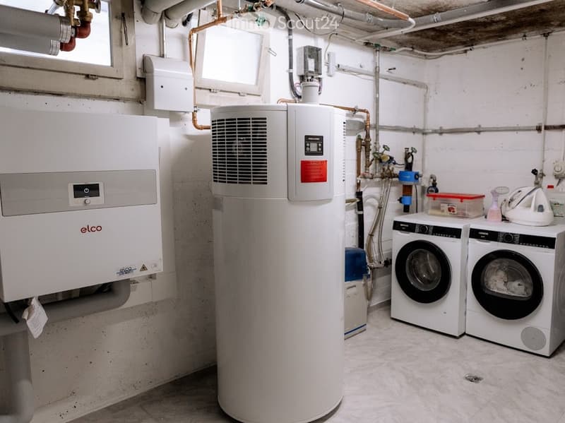 Utility room with a washing machine, dishwasher, and water heater, featuring exposed pipes and a small window.
