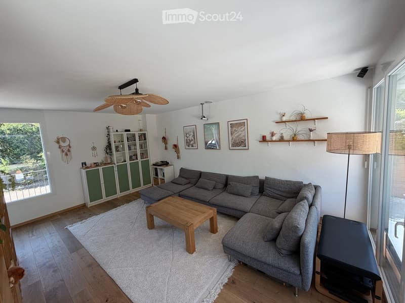 Modern living room with grey sectional sofa, wooden coffee table, white shag rug, built-in cabinet, and wall-mounted shelves with decorative items.