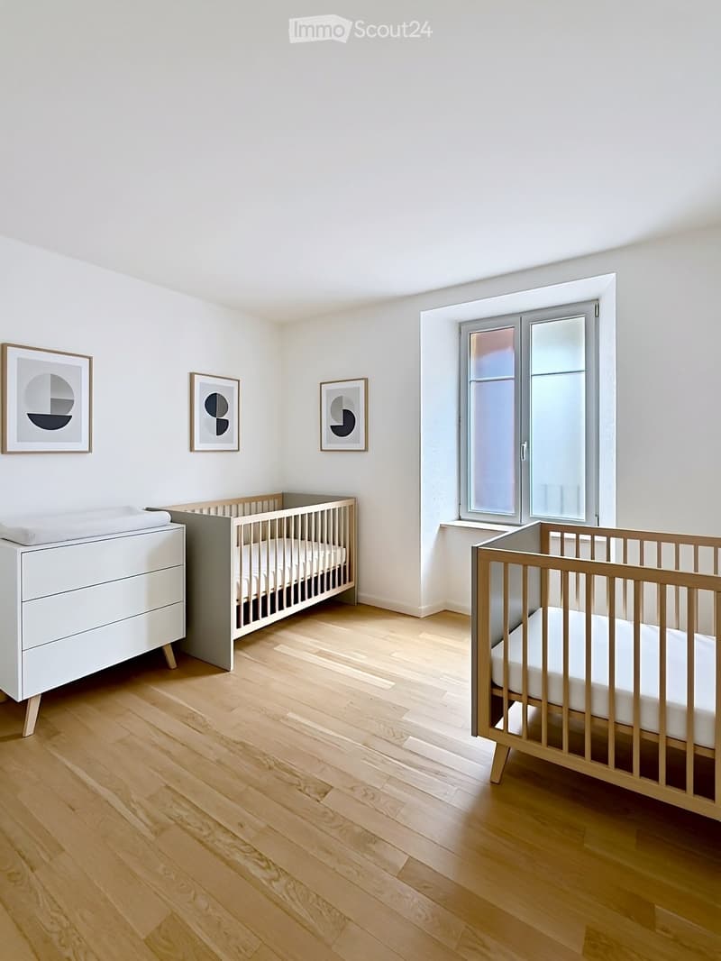 Minimalist nursery with wooden cribs, white dresser, and modern artwork on the walls.