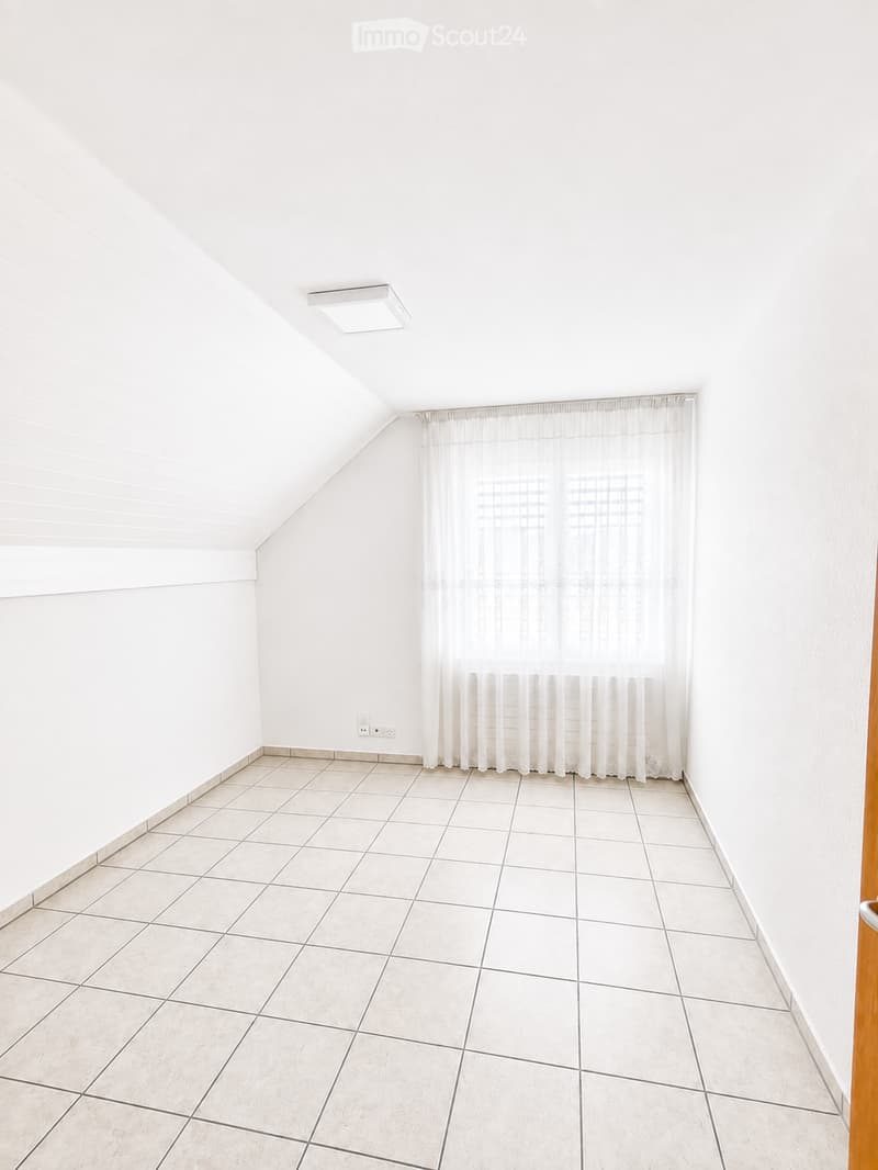 Empty room with white walls, tiled floor, and a window with white curtains. No furniture or equipment is present.