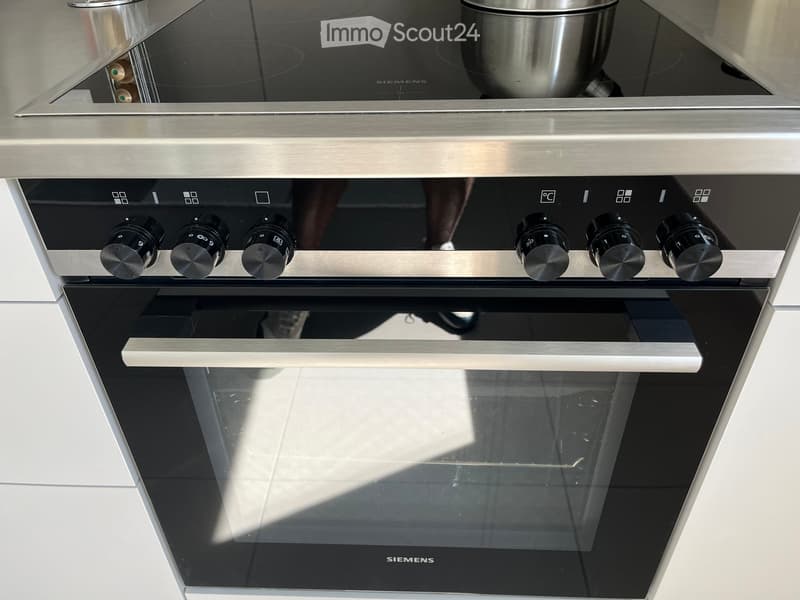 Modern stainless steel oven with multiple control knobs and a large glass door, featuring a sleek design and brand name 'SIEMENS' visible on the front.