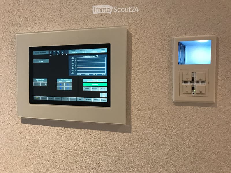 Wall-mounted home automation system with a large touchscreen display and a smaller control panel featuring buttons and a small screen.
