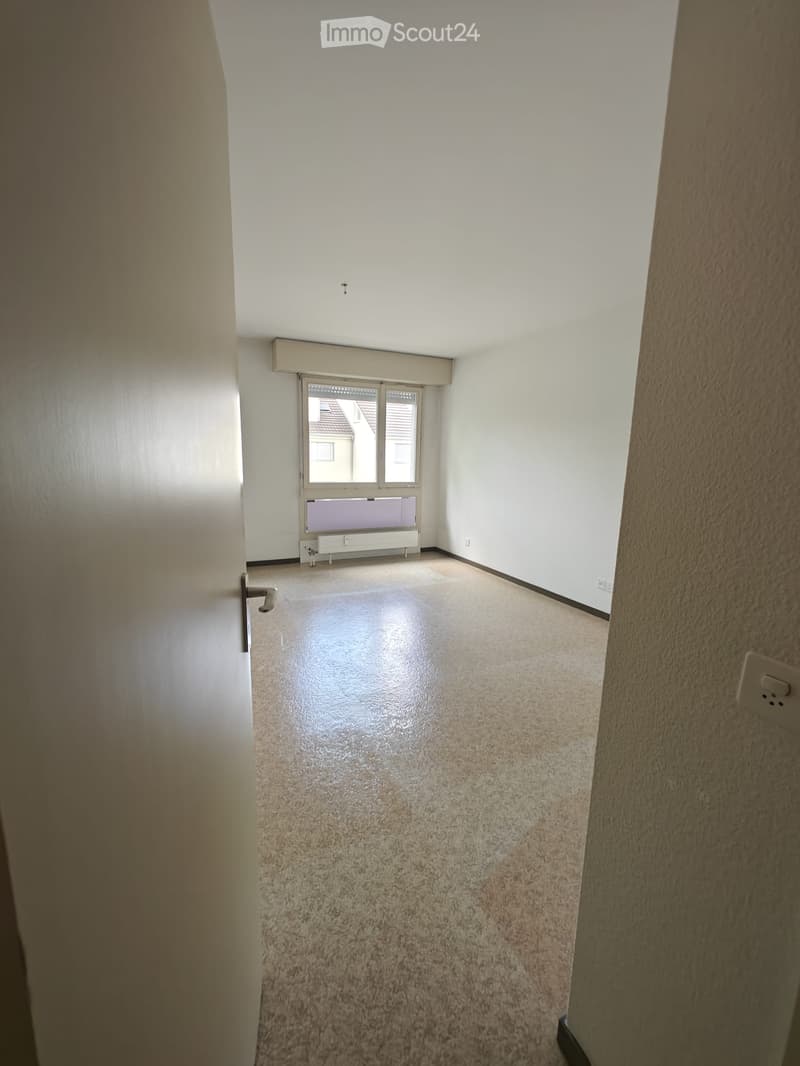 Empty room with beige carpeted floor, white walls, and a window with blinds. No furniture or equipment present.