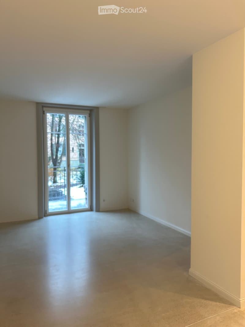 Empty room with light-colored walls, carpeted floor, and large sliding glass door leading to an outdoor area.