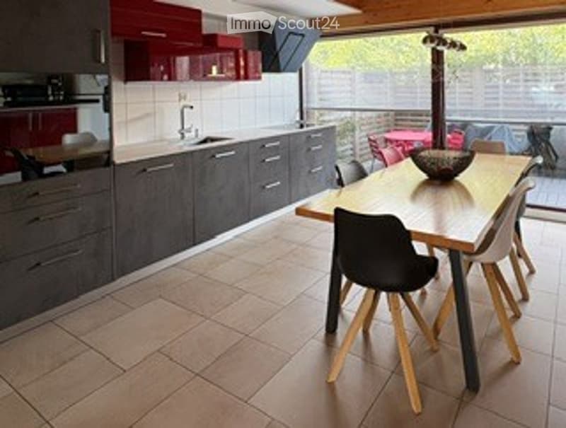 Modern kitchen and dining area with grey cabinets, a sink, a dining table with chairs, and a decorative bowl on the table.