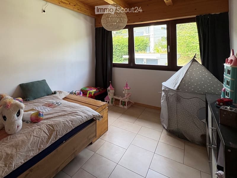 A cozy children's bedroom with a wooden bed, a large window, a tent, and various toys including a unicorn plush and a toy castle.