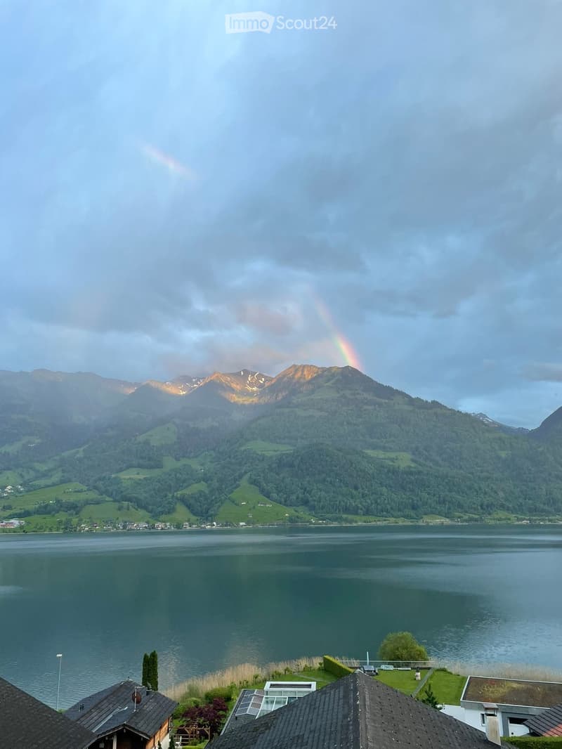 Mountain landscape with lake, rainbow, house with solar panels