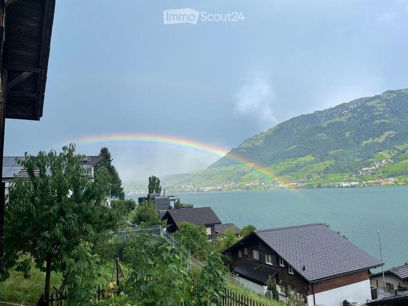 Lake view from balcony of house with mountain backdrop and rainbow