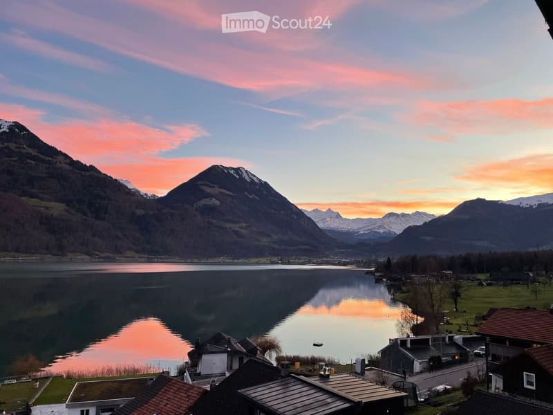 Lakeside view of mountains with a sunset in the sky.