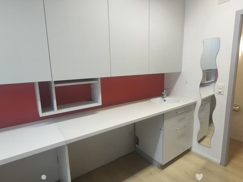 Modern bathroom with white cabinets, a red accent wall, a sink, and a stylish mirror.