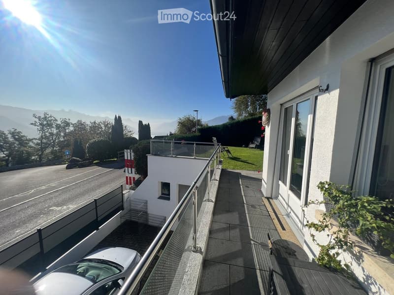 Balcony with metal railing, tiled floor, and a view of a road and surrounding greenery.
