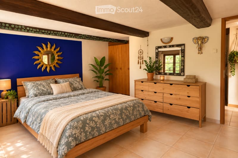 Cozy bedroom with a wooden bed, patterned bedding, nightstand with lamp, dresser with mirror, and decorative wall pieces including a sun design and elephant head.