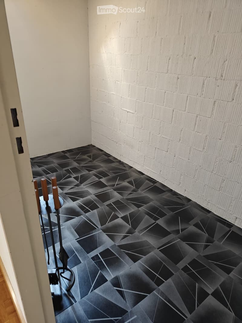Empty room with white brick wall and black geometric tiled floor. No furniture or equipment visible.