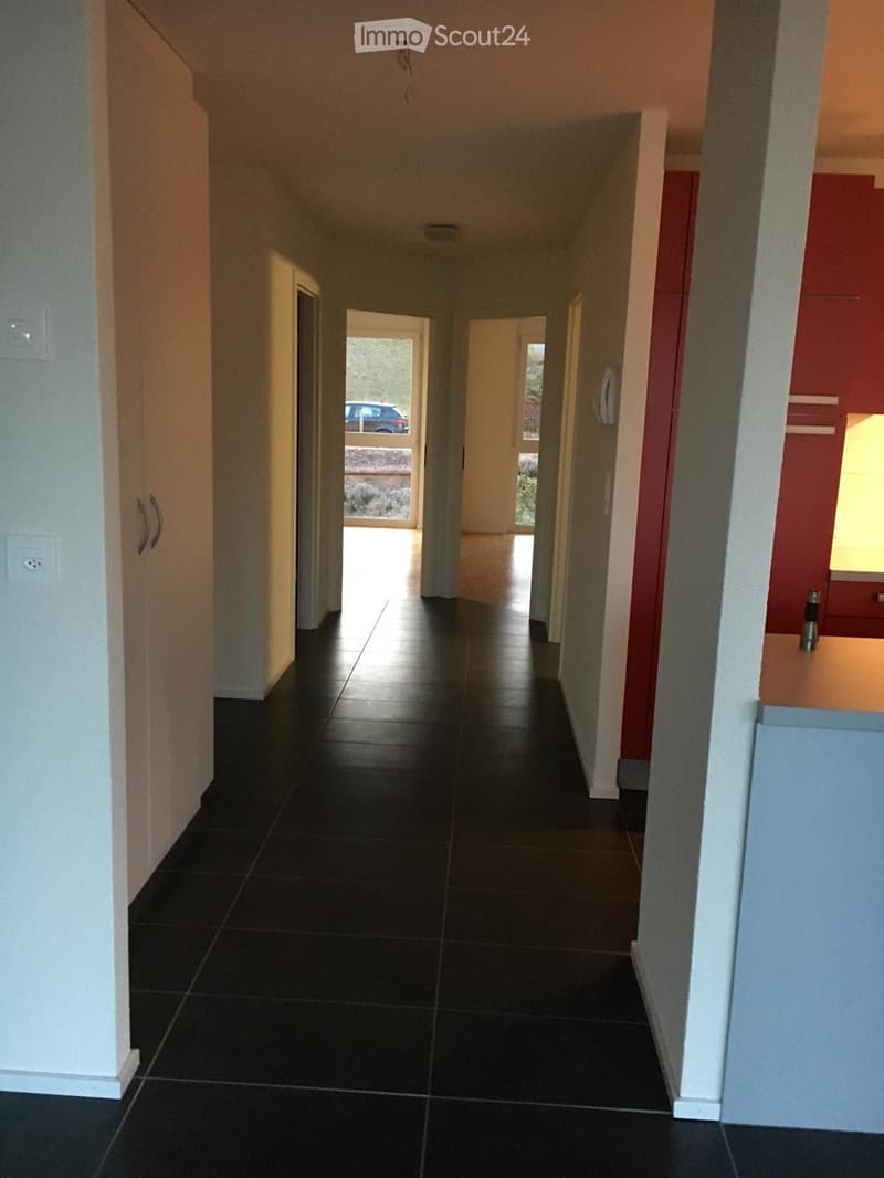 Black tiled floor, white walls, doorways leading to various rooms, car visible outside