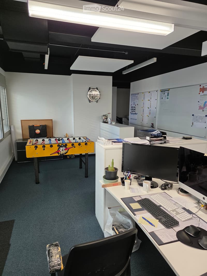 Office space with a desk, computer, keyboard, mouse, cup, notepad, and a small foosball table in the corner.