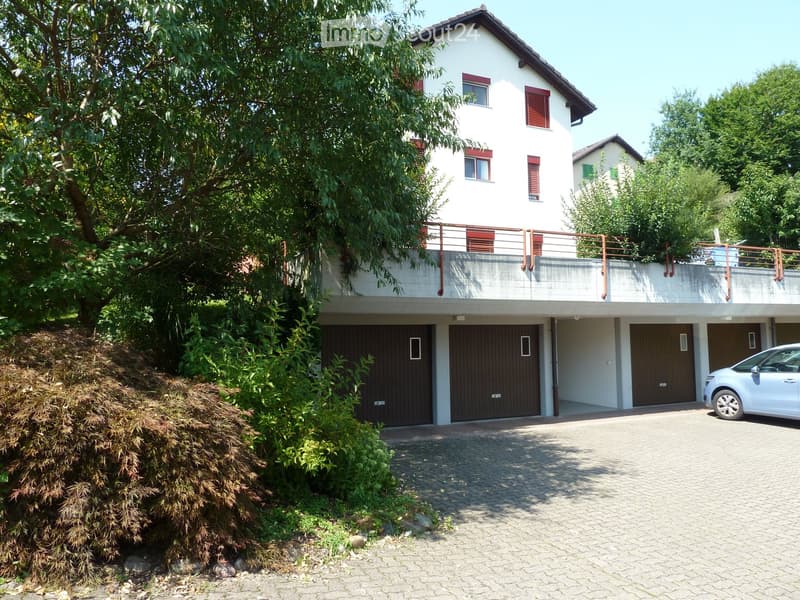 2 story house, white exterior, brown garage doors, balcony, car parked in front