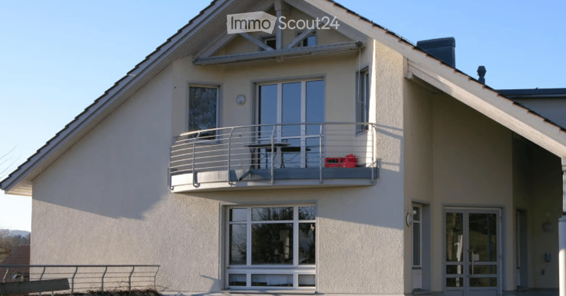 Two-story house with a balcony, large windows, and a modern design.