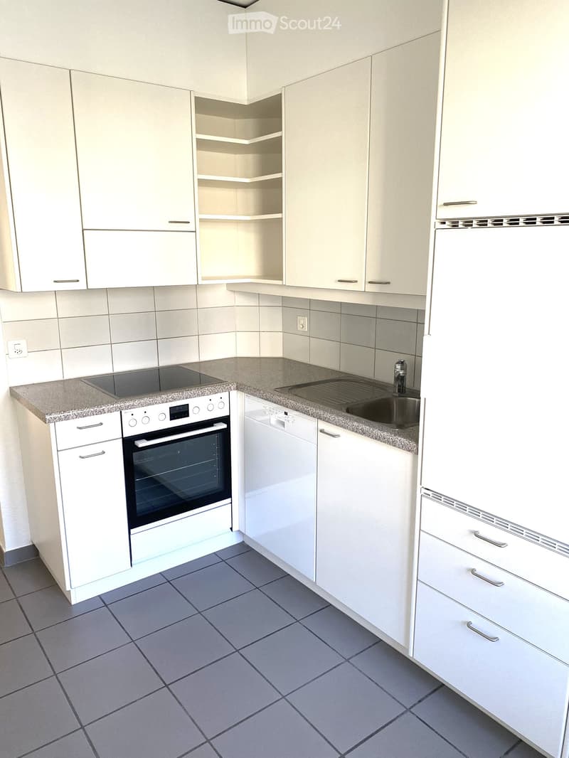 Modern kitchen with white cabinets, granite countertops, built-in oven, dishwasher, and sink.