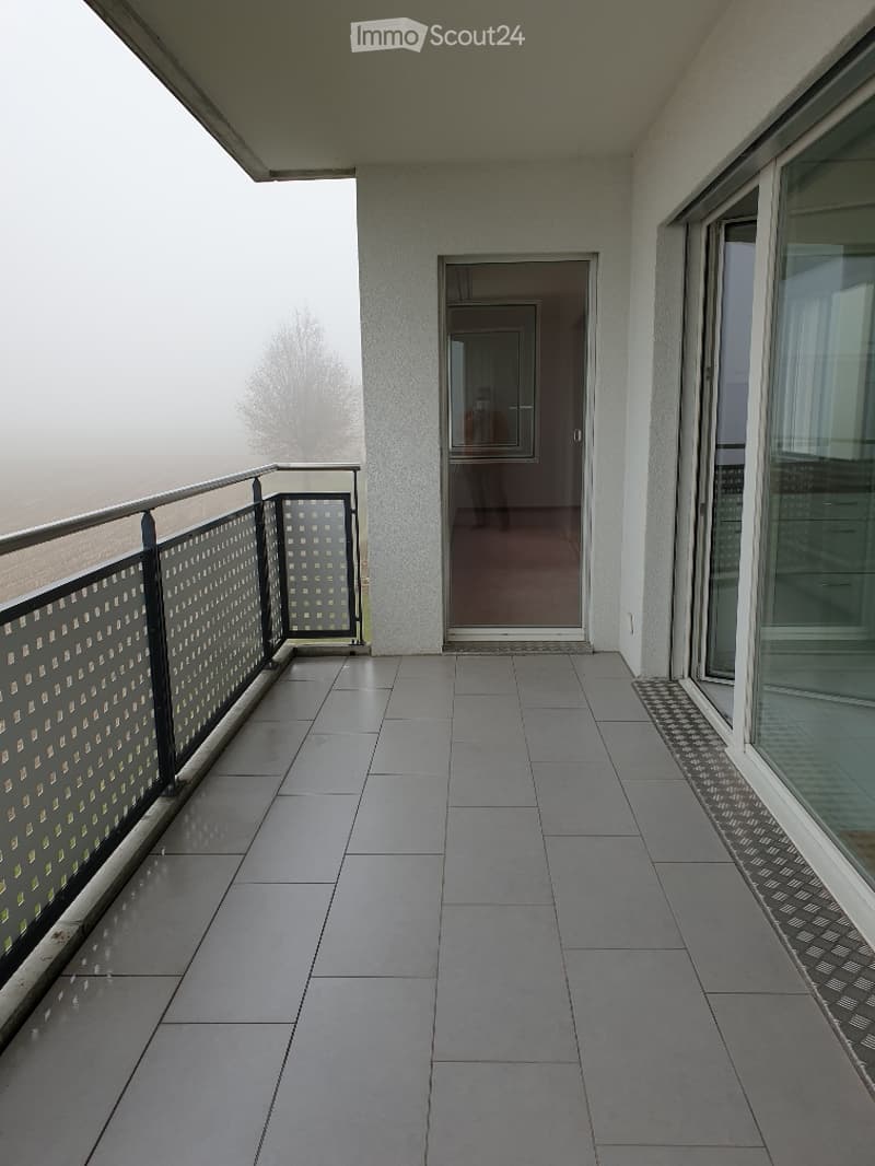 Balcony with tiled floor, metal railing, and a view of a foggy landscape.