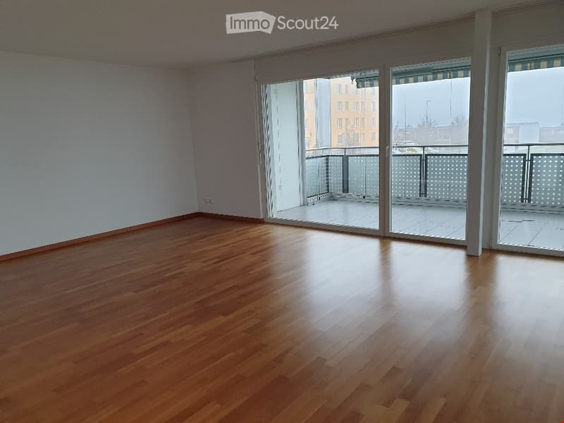 Empty room with wooden flooring and large sliding glass doors leading to a balcony.