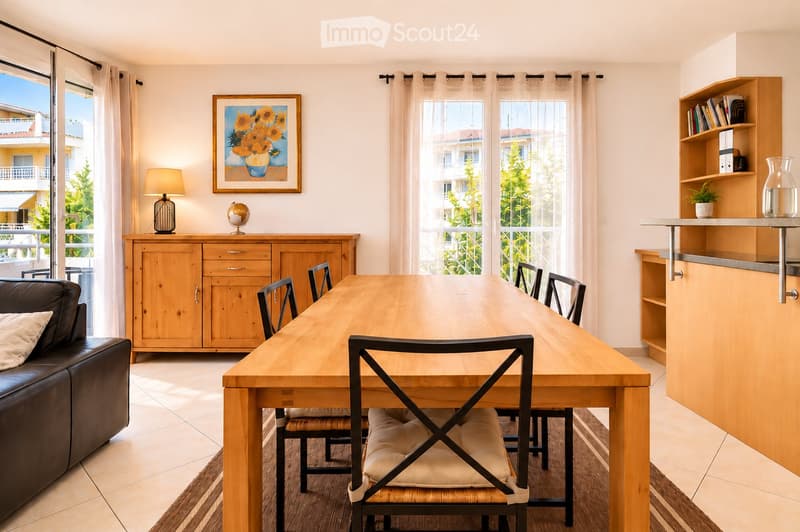 Bright, open living and dining area with large windows and sliding glass doors leading to a balcony. Features a wooden dining table with six chairs, a leather sofa, a wooden cabinet with drawers, a floor lamp, a globe, a picture frame, a bookshelf, and a