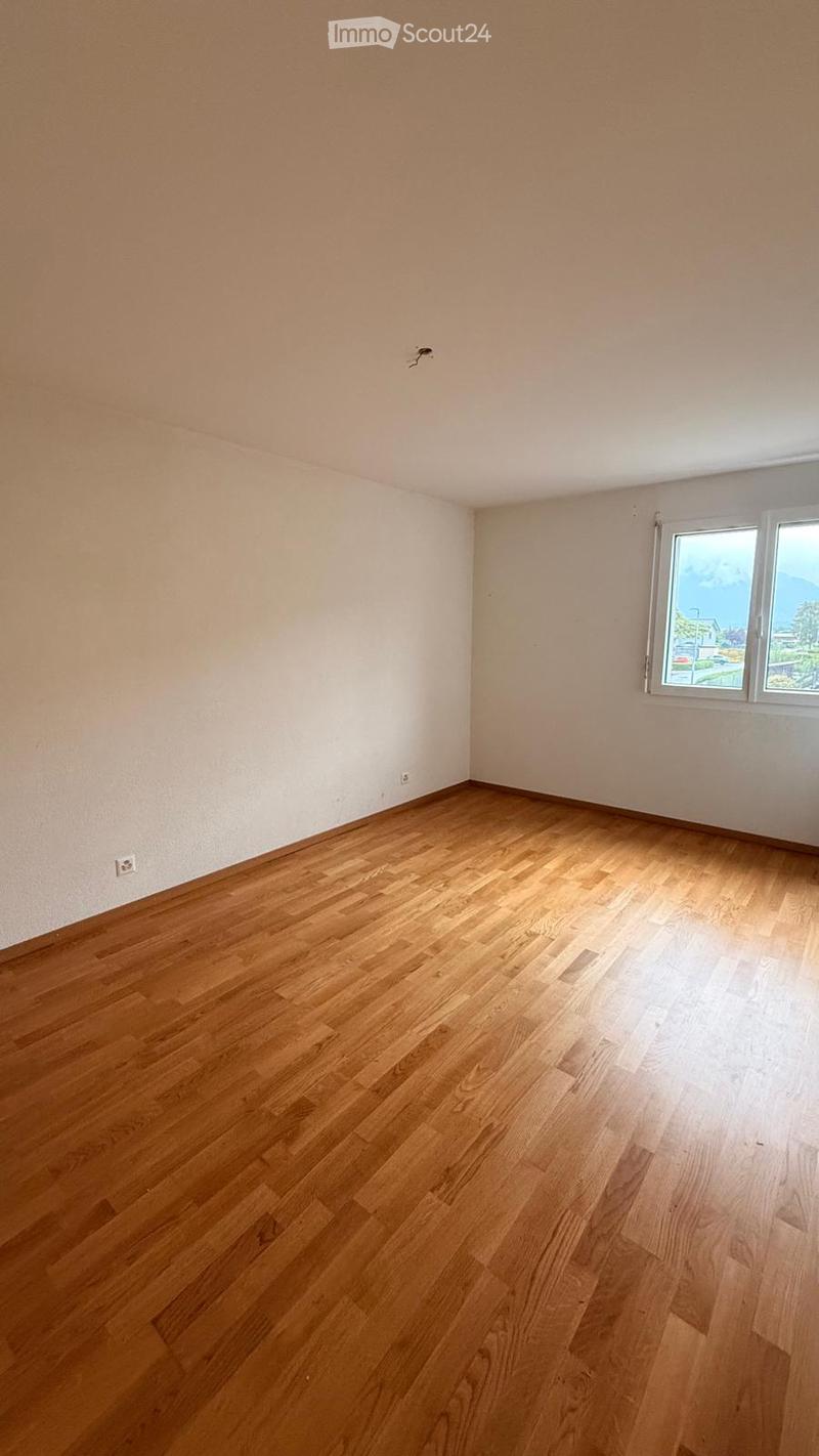 Empty room with wooden flooring and white walls, featuring a window with a scenic view.