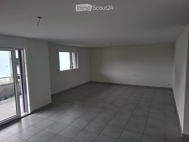 Empty room with tiled floor, white walls, and a large sliding glass door leading to a balcony.