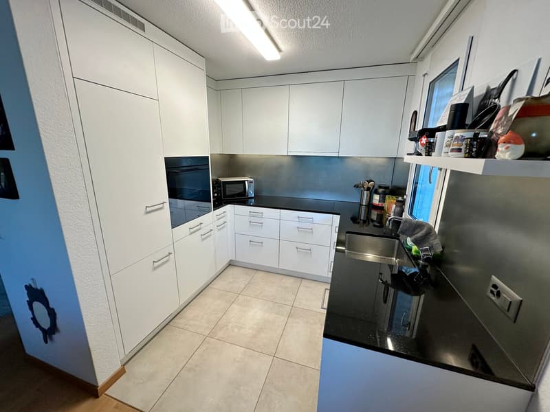 Modern kitchen with white cabinets, stainless steel appliances, and a black countertop.
